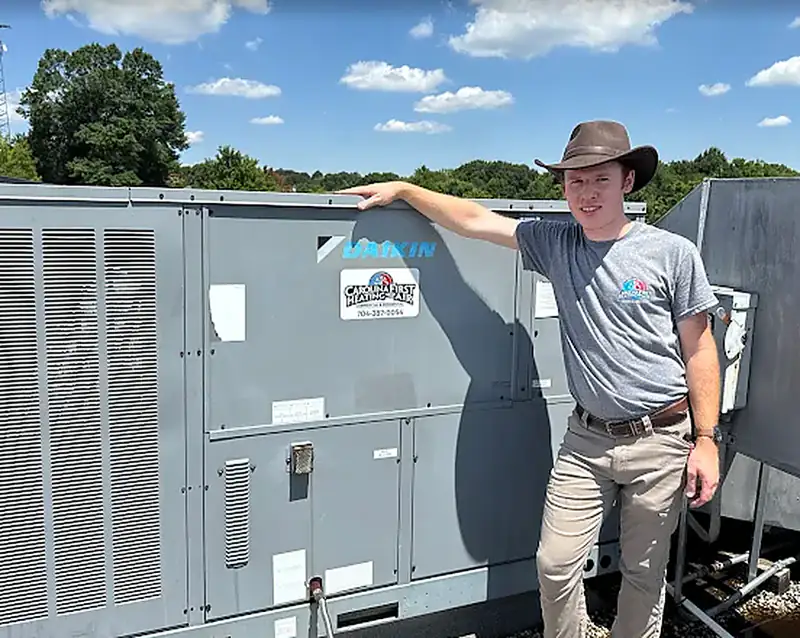 Carolina First technician standing beside a Daikin commercial rooftop unit