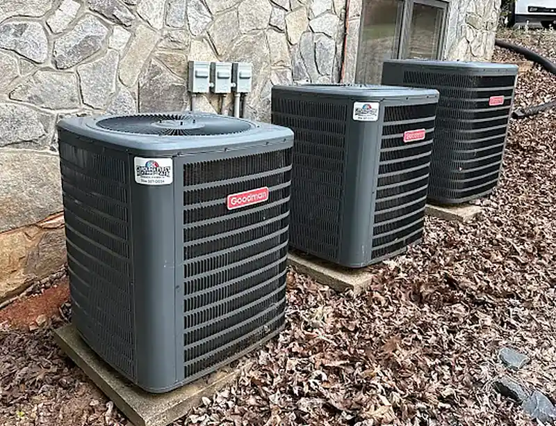 Three new Goodman outdoor condensers lined up beside a house