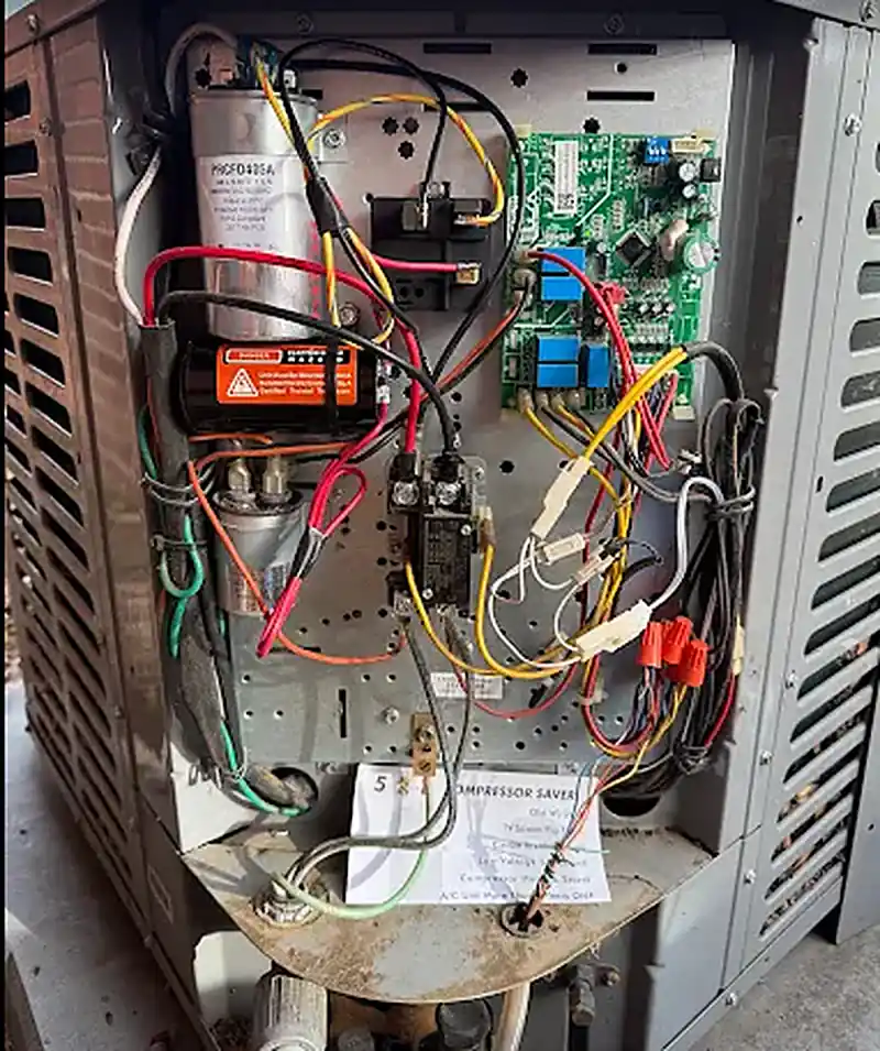 Outdoor condenser control board, capacitor, and wiring exposed for repair