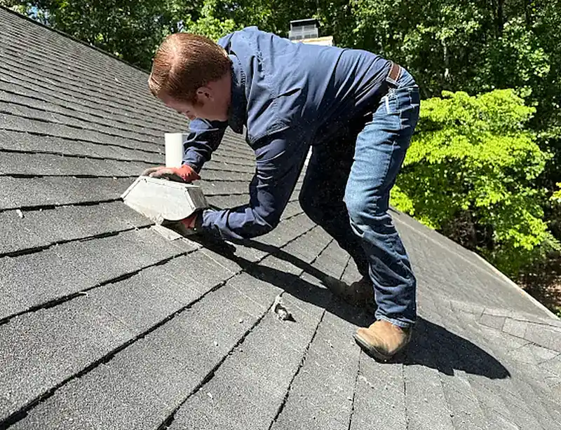 Technician on a roof cleaning a dryer vent termination
